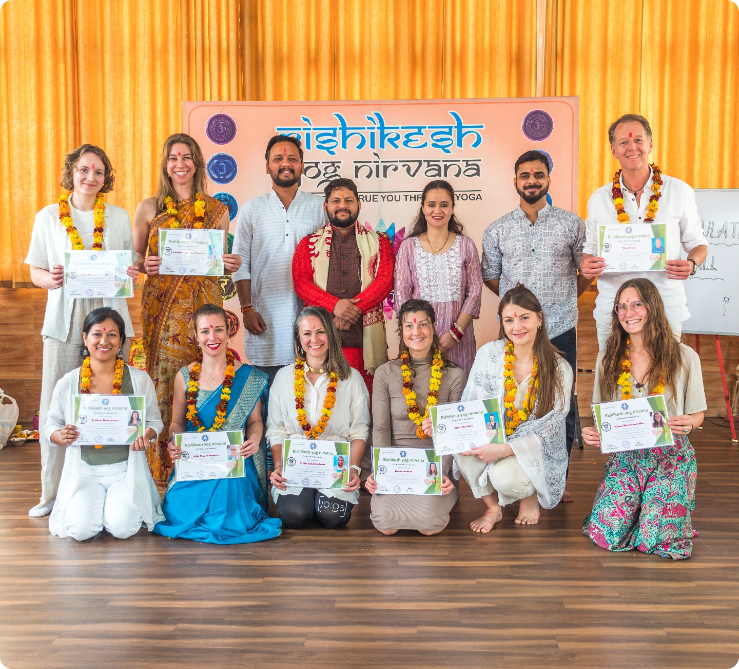 Graduates of a yoga teacher training program at Rishikesh Yog Nirvana holding certificates, representing the shared path forward in yoga practice and teaching