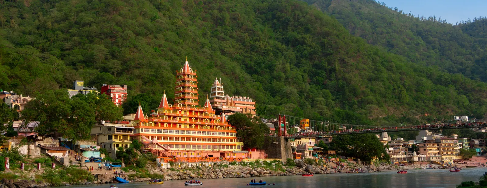 Tera Manzil temple and Laxman Jhula bridge on the Ganga at Rishikesh, with rafts on the river