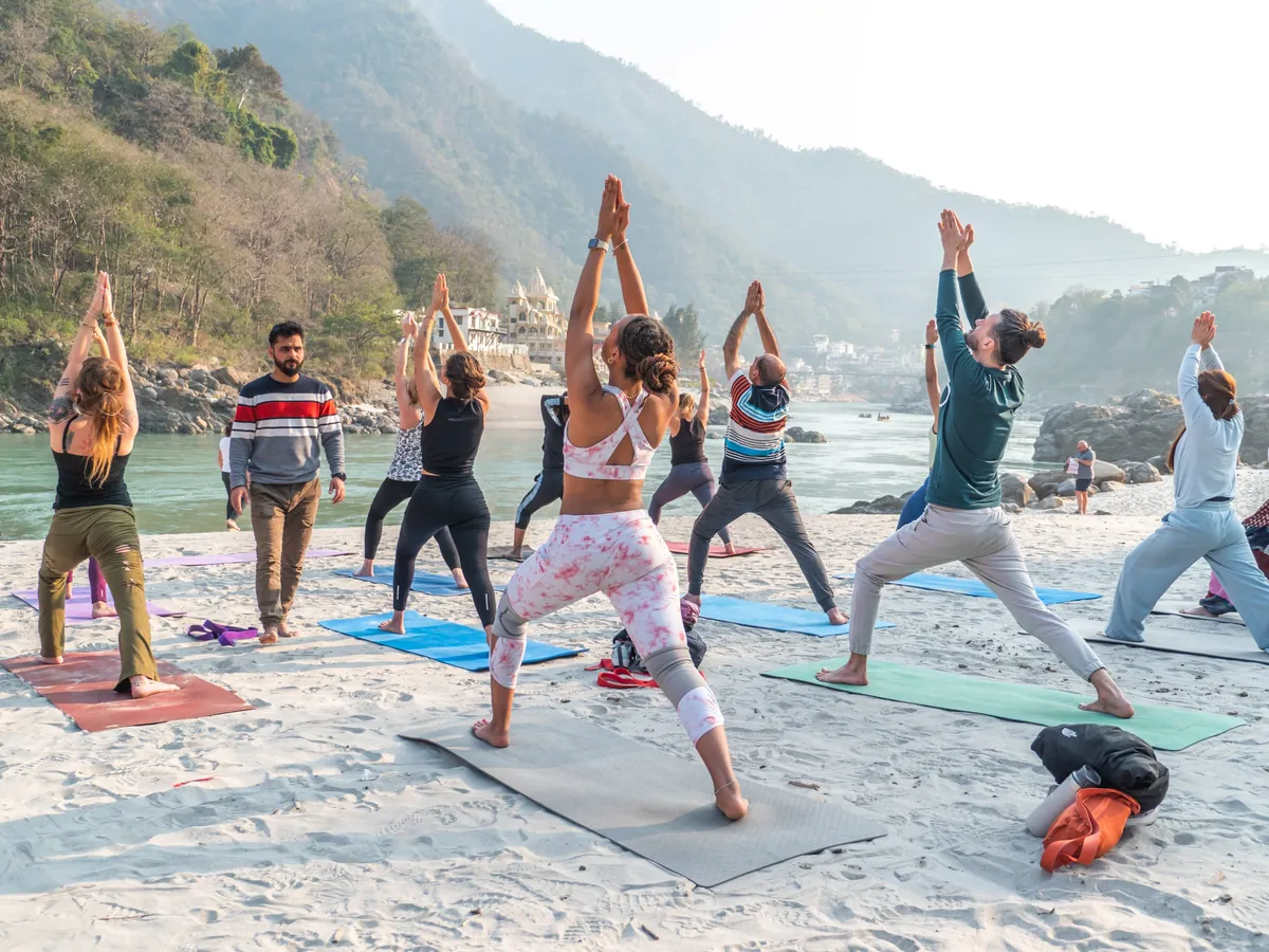 Students practising a morning yoga class on the sand beside the Ganga in Rishikesh