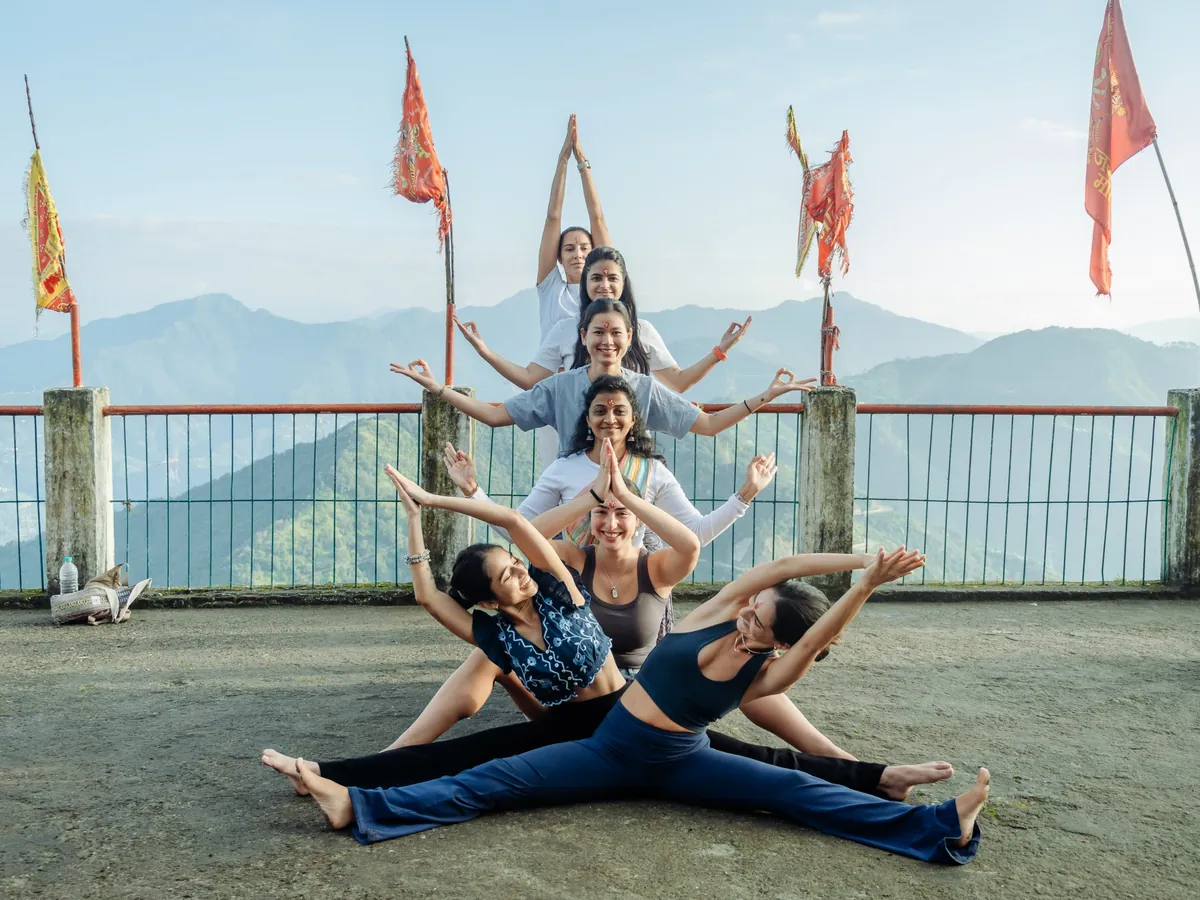 A group of students posing together on the school rooftop with prayer flags and the mountains behind