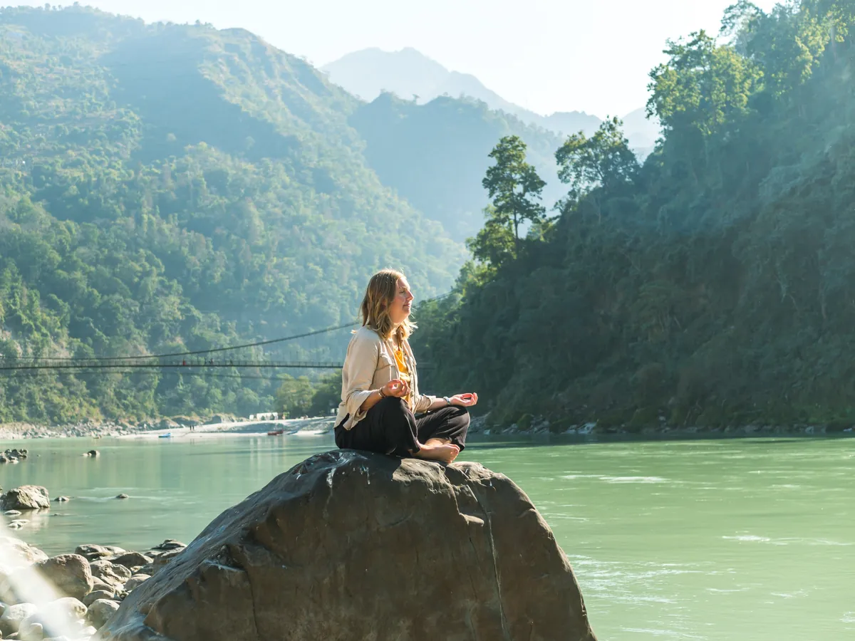 A student meditating on a rock above the Ganga near Laxman Jhula in Rishikesh
